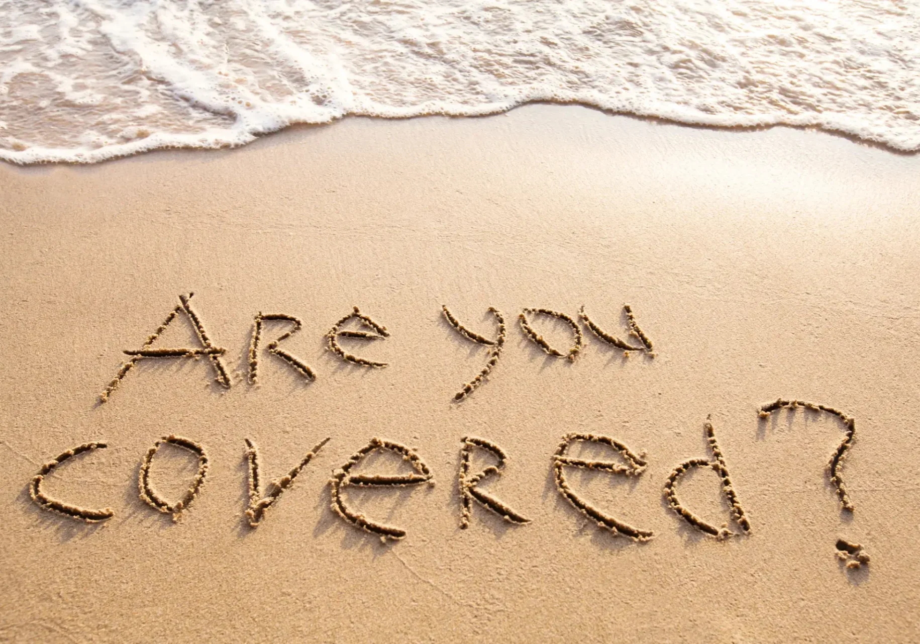 Text 'Are you covered?' written in sand