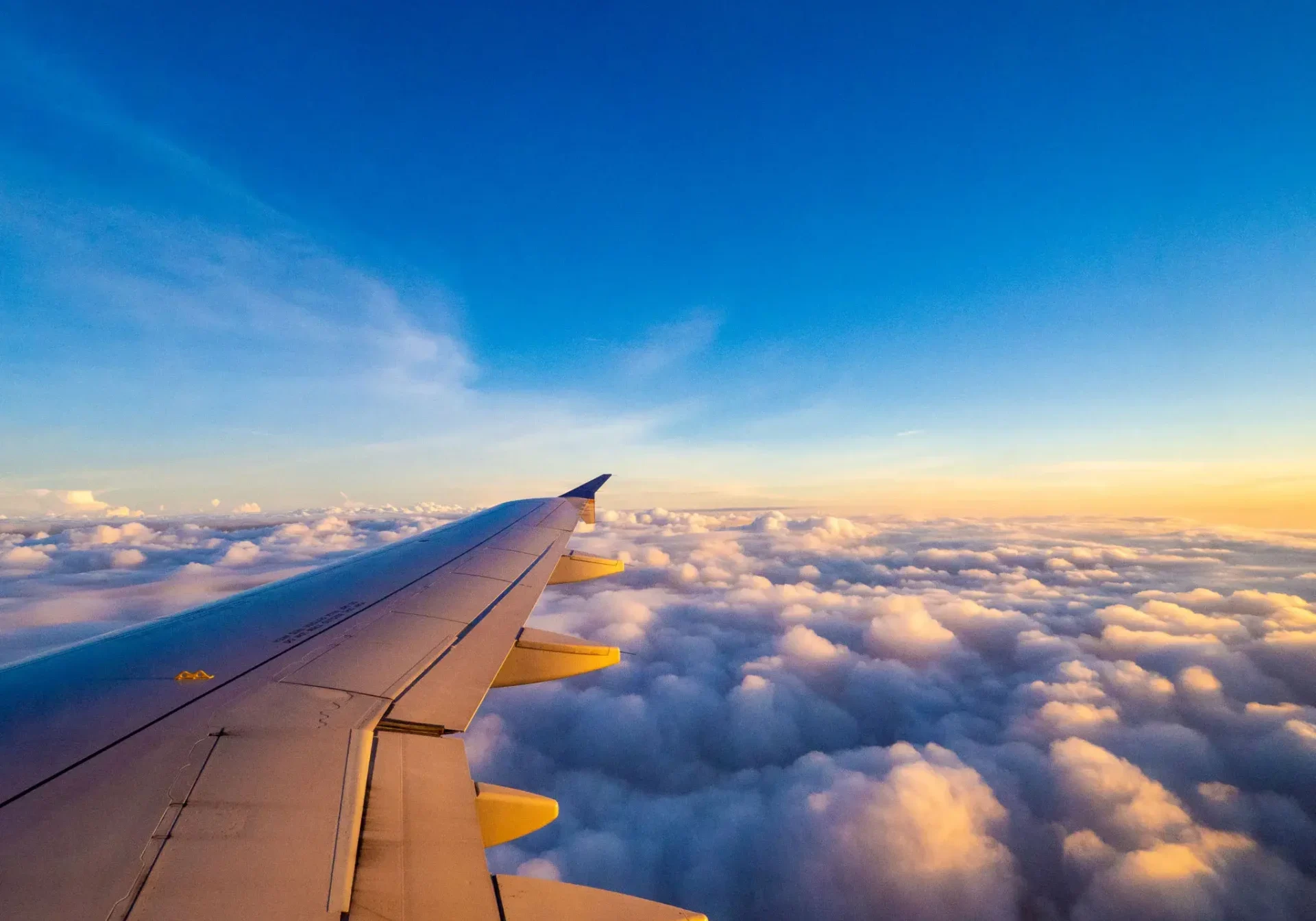 Airplane wing above clouds at sunrise